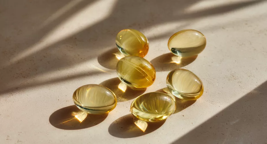 Yellow gel capsules on surface with shadow